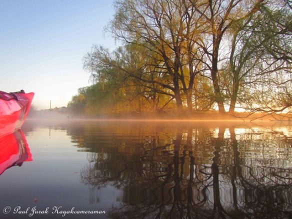 A narrow beam of light  highlights the morning mist. 